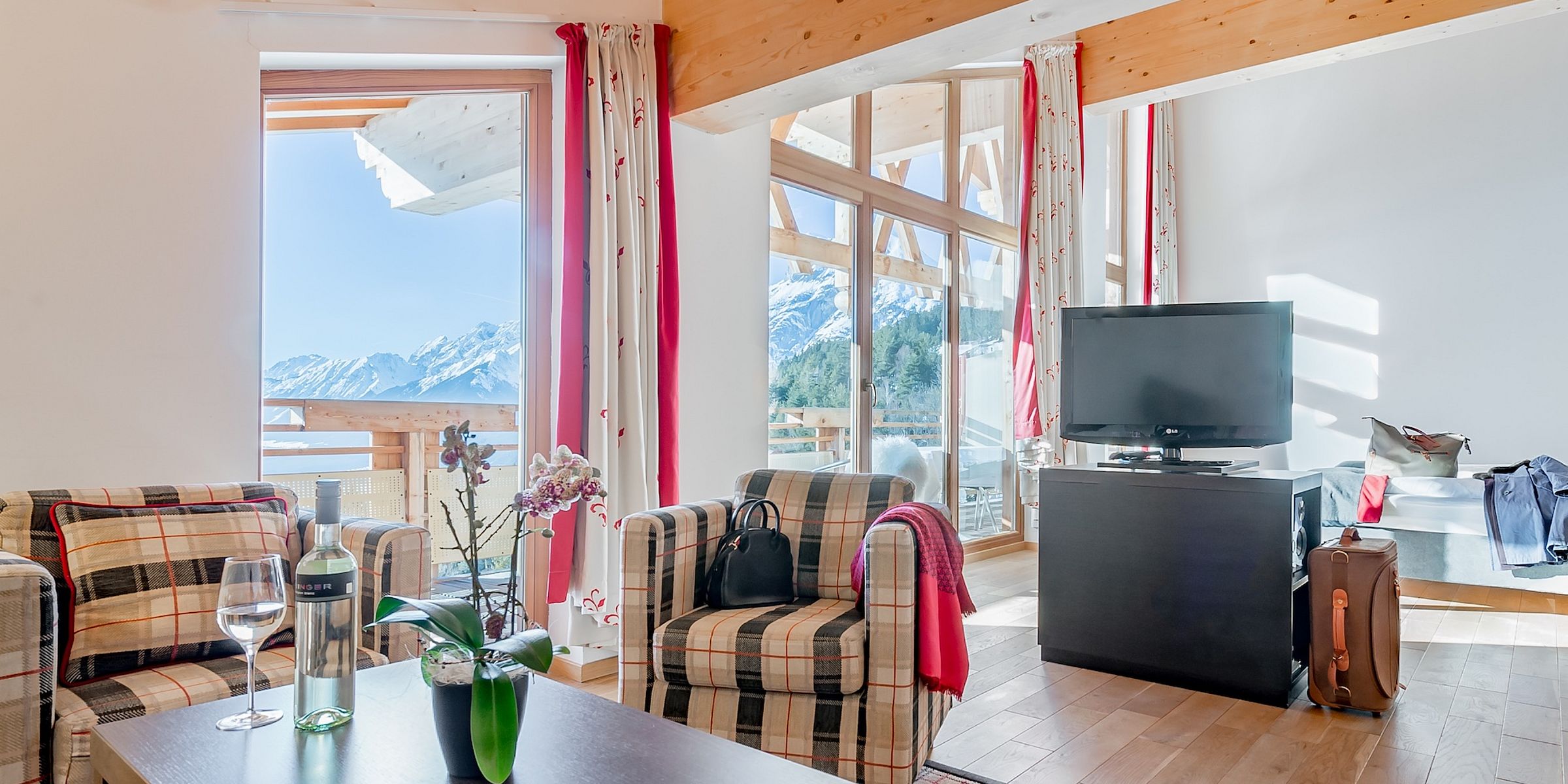 Wohnraum einer Suite im Hotel Inntalerhof mit Panoramafenstern und Blick auf verschneite Berge
